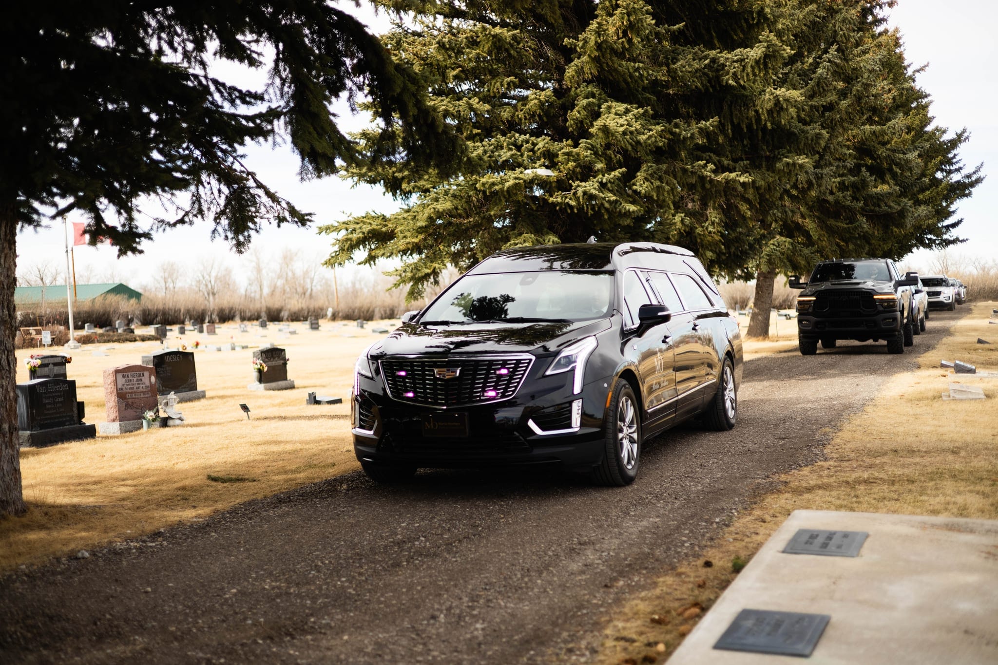 A black Cadillac Escalade lead vehicle waiting at a Lethbridge cemetery