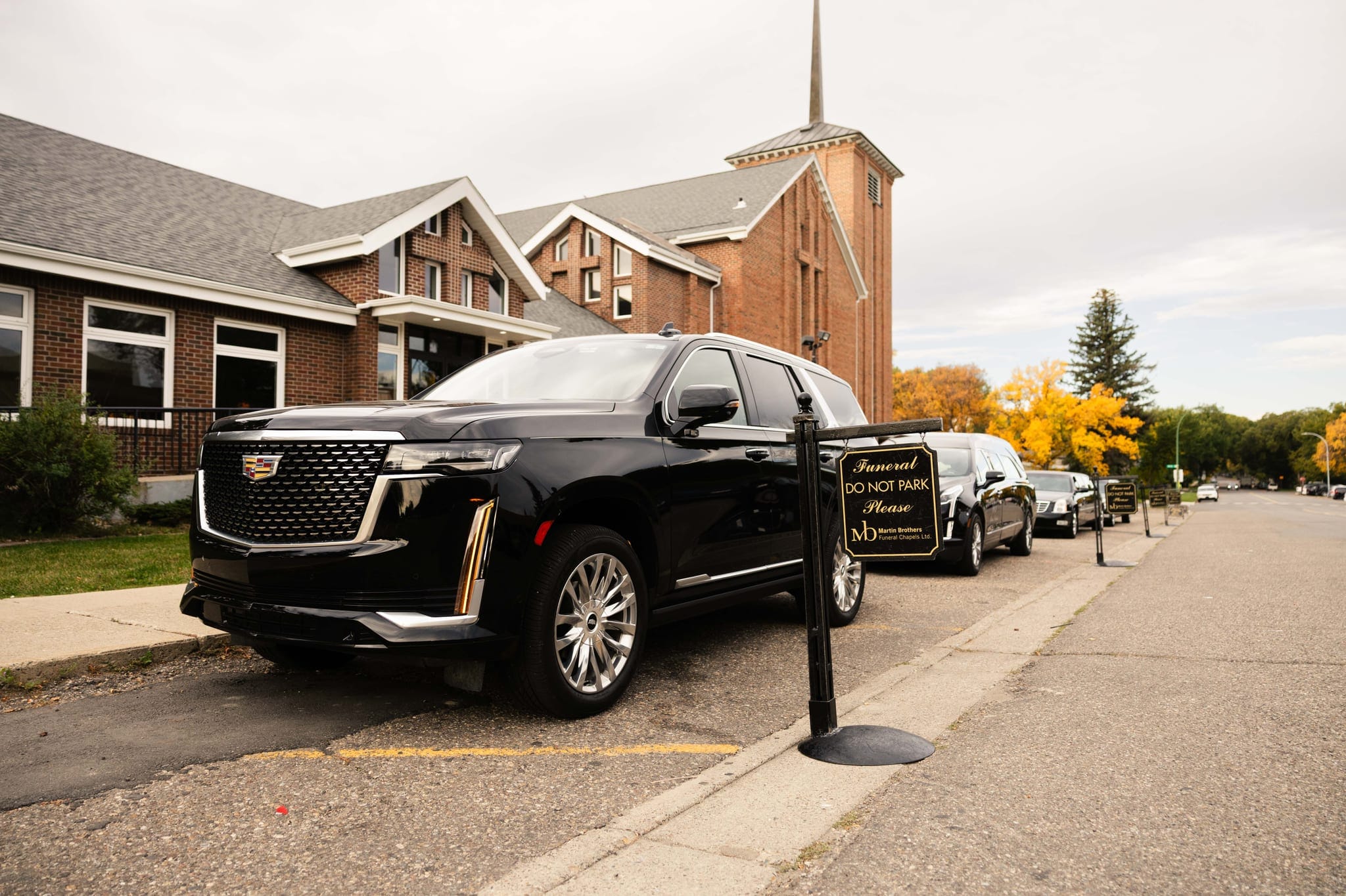 A black Cadillac Escalade waiting outside a Lethbridge church on an autumn afternoon