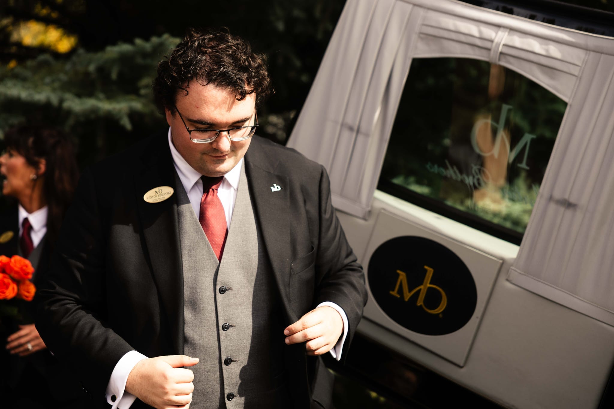 A Martin Brothers director beside the funeral coach, its door bearing the gold Martin Brothers crest