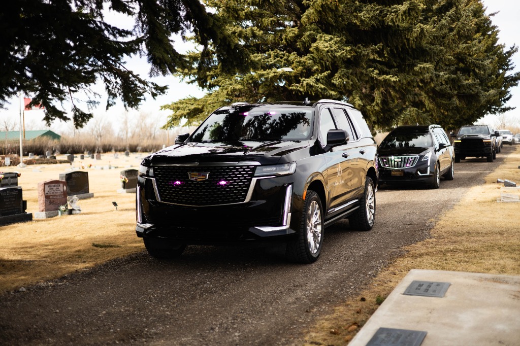 Elegant black Cadillac Escalade funeral lead vehicle arriving at a cemetery in Lethbridge